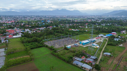 Aerial view of rice field with high voltage electric transformer substation.