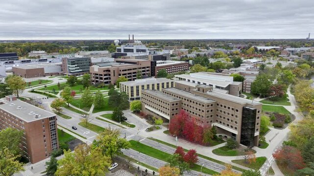 Aerial drone footage of college campus on a cloudy fall day in October in East Lansing Michigan near the red cedar river. College dorms, apartments visible. Beautiful autumn colors everywhere