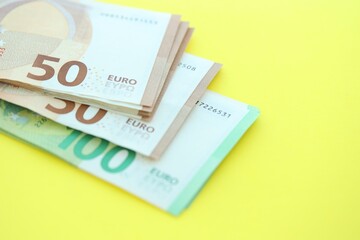 Big amount of one hundred and fifty euro money bills on yellow background