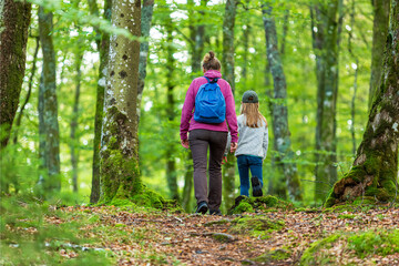 Fototapeta premium Woman and a girl walking on a path in a deciduous forest