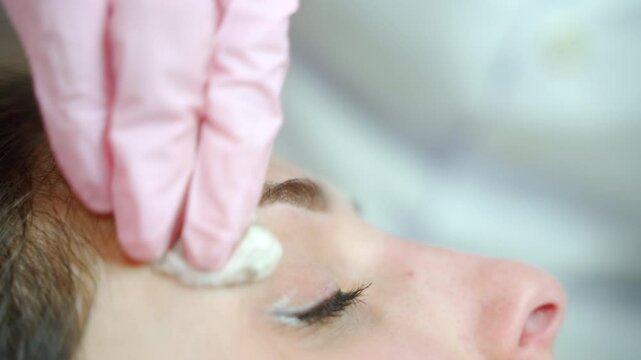 Microblading performance for a client. Master's hands in latex gloves use tattoo machine. Close up.