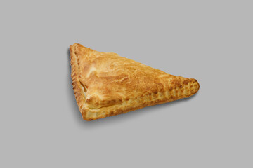A triangleshaped pastry is set against a gray background surface