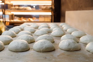 A chunk of dough is resting on a wooden table in a bakery © pavelvozmischev