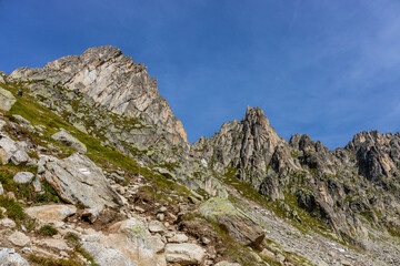 Alps scenic landscape on Tour du Montblanc. Rocky and snow summit peaks of the Alps on the trekking route TMB around Mont Blanc in Chamonix and Courmayeur. Alpine scene with mountains and lakes 