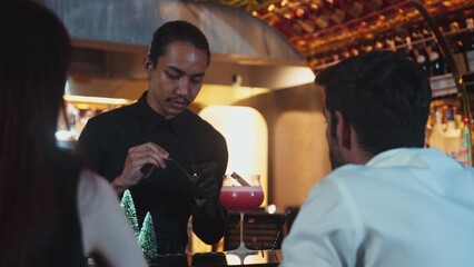 Focused on mixed punch cocktail Christmas theme garnishing with burning cinnamon and star anise by bartender, serving decorated green neon snow Christmas tree bar special cool drink luxury. Vinosity.