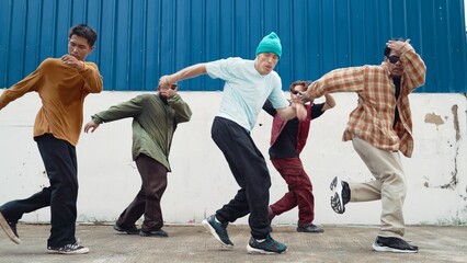 Group of hip hop choreographer dancing street dance together at wall. Young break dancer practicing break dance, moving to modern rhythm, express feeling of lively. Outdoor 2024. Hiphop.