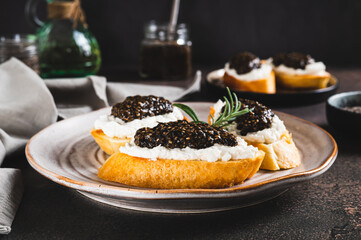 Delicious sandwiches with ricotta and black chia caviar on a plate on the table