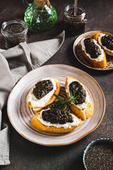 Bruschetta with cream cheese and black chia caviar on a plate on the table vertical view