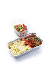 a white background disposable plastic and foil tableware airplane food snack mashed potatoes with chicken fillet with fresh vegetables healthy nutrition