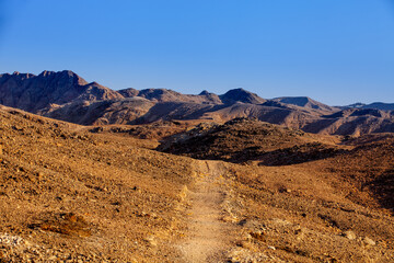 Lifeless hills near Red sea gulf and narrow path from desert to the coastline of the sea. Blue color sky add a contrast between blue sea surface, blue color heaven and dark brown hills