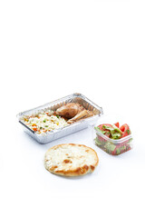 a white background disposable plastic and foil tableware airplane food snack Chinese steamed rice with vegetables with chicken leg with freshly chopped vegetables and bread flatbread