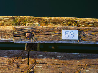 Weathered wooden pier with number plate fifty-three along the calm water at sunset