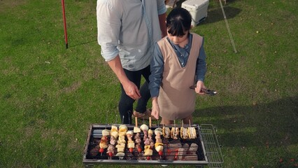 Family gather camp in garden, Father and daughter grill food for family member. Outdoor camping...