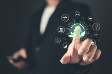 A person touches a glowing net zero icon surrounded by symbols of sustainability and ecology, representing environmental goals, renewable energy, and efforts for a greener and cleaner future.