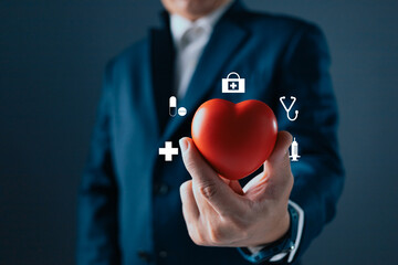 A person in a suit holds a red heart, surrounded by medical icons like a stethoscope, syringe, and...