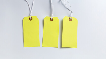 Blank yellow tags hanging on strings on white background
