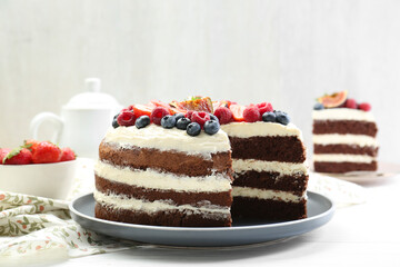 Delicious chocolate sponge cake with berries served on white wooden table, closeup