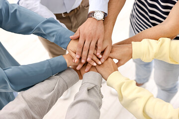 Teamwork. Group of employees joining hands in office, closeup