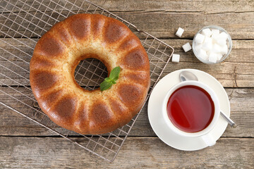 Freshly baked sponge cake, sugar cubes and tea on wooden table, top view
