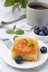 Slice of tasty semolina cake served on white textured table, closeup