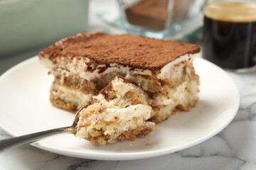 Piece of tasty tiramisu on white marble table, closeup