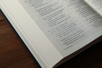 Open Holy Bible in English language on wooden table, closeup