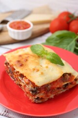 Piece of delicious cooked lasagna with basil on table, closeup