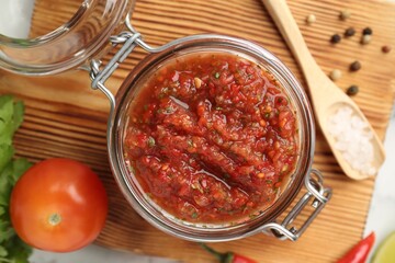 Spicy salsa and ingredients on white table, top view