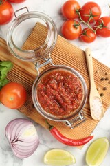Spicy salsa and ingredients on white marble table, flat lay