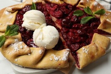 Tasty galette with cherries and ice cream on white table, closeup