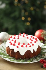 Traditional Christmas cake decorated with red currants and rosemary on wooden table