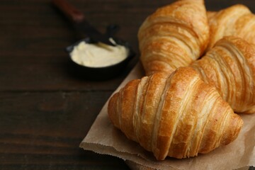 Tasty fresh croissants served with butter on wooden table, closeup. Space for text