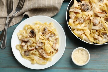 Tasty Alfredo pasta with chicken served on light blue wooden table, flat lay