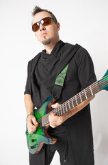 Stylish musician standing and posing with a green electric guitar