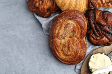 Different delicious pastries and butter on grey table, top view. Space for text