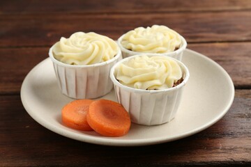 Delicious carrot muffins and fresh vegetable on wooden table, closeup