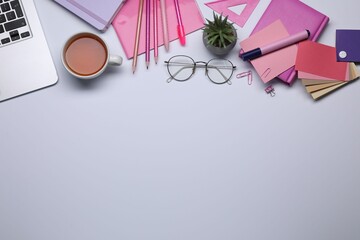 Designer's workplace with stationery, color palettes and cup of tea on grey table, flat lay. Space...