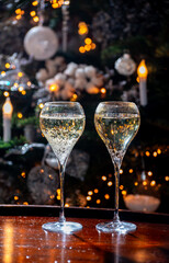 New year or christmas dinner, glasses of brut champagne or cava, prosecco sparkling wine with christmas tree and garland lights on background