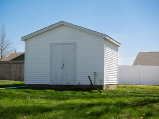 Backyard Shed. A suburban backyard shed with an overturned chair in front in springtime.