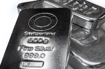 Three silver cast bars of different weight in a pile isolated on the white background. Selective focus.