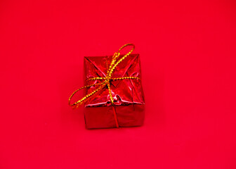 A red gift box with a gold ribbon on a striking red background