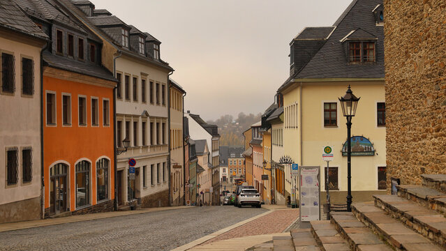 Blick die Gro&szlig;e Kirchgasse hinab mit historischer Steintreppe der St. Annenkirche in Annaberg-Buchholz, Erzgebirgskreis, Sachsen, Deutschland, farbenfrohe Altstadtfassaden im Erzgebirge bei D&auml;mmerung.