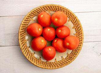 Fresh juicy tomatoes on a ceramic plate on a wooden table, macro, top view.