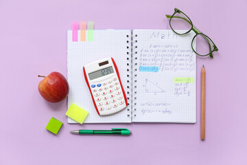 Notebook with apple, eyeglasses and school stationery on lilac background