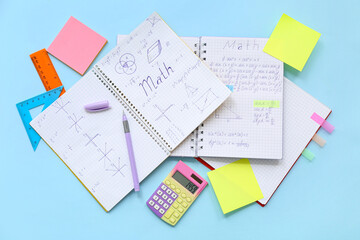 Notebooks with calculator and school stationery on blue background