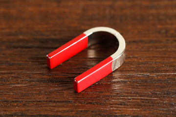 One horseshoe magnet on wooden table, closeup