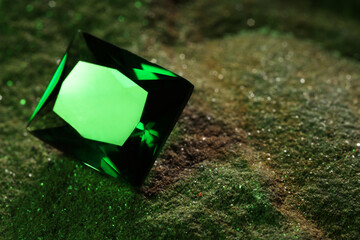 Beautiful shiny green gemstone on stone, closeup. Space for text
