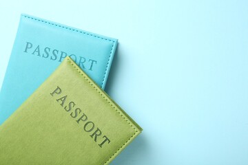 Fototapeta premium Passports in color covers on light blue background, top view. Space for text