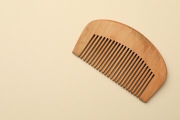 One wooden hair comb on beige background, top view. Space for text