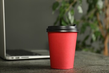 Paper cup on grey textured table indoors, closeup. Mockup for design
